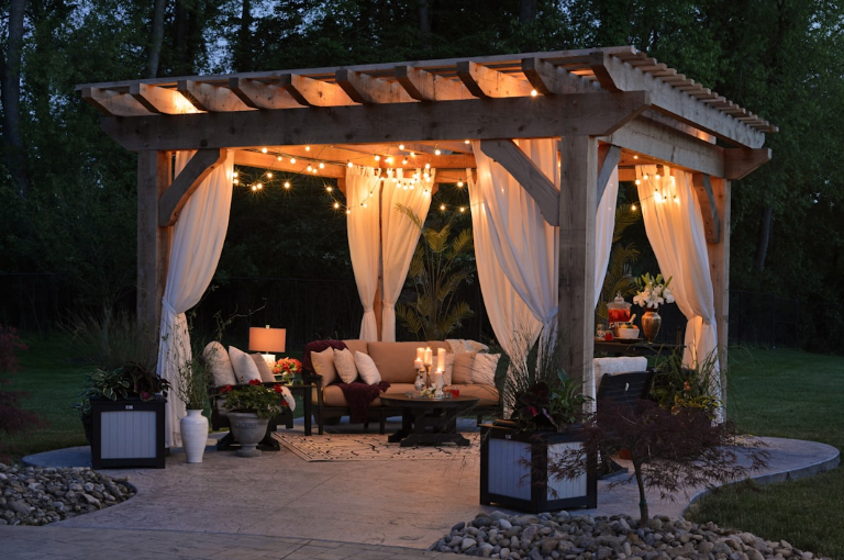 Elegant wooden pergola with string lights and draped curtains in a Fort Worth TX backyard, designed for cozy evening outdoor living