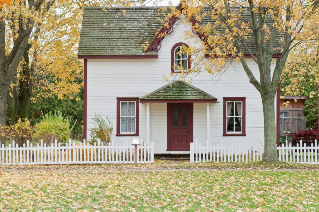 White picket fence in front of house showcasing results of expert staining services.