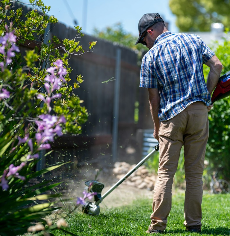 Texas Patio and Fence professional trimming lawn edges in Fort Worth as part of custom landscape design with patios, lighting, and water features