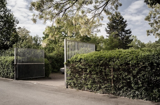 Modern steel driveway gate surrounded by greenery, enhancing home security and curb appeal.