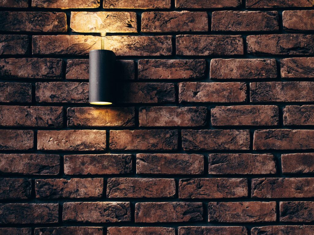Alt Text: Modern outdoor brick wall with warm lighting. custom stonework inspiration for Fort Worth patios.