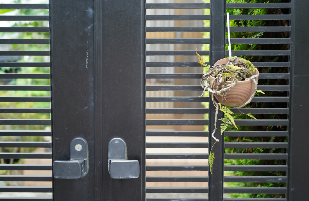 Electric gate with handles and hanging planter, showing maintenance needs