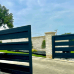 Modern black metal electric gate installed by Texas Patio and Fence, showcasing durable craftsmanship and automated entry design suitable for Texas weather.