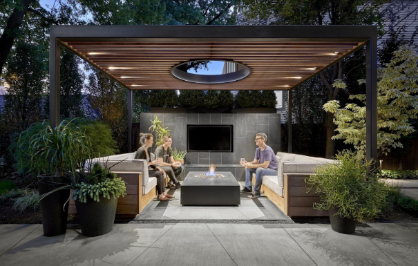Modern metal pergola with seating area and fire pit in a landscaped backyard