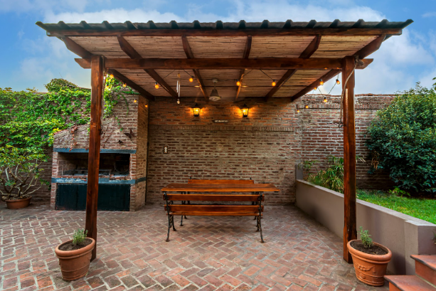 Custom patio installation in Fort Worth featuring a covered brick patio with wooden pergola, built-in seating, and outdoor fireplace